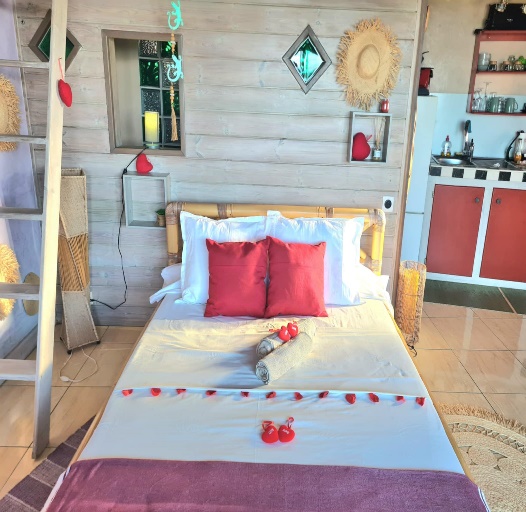 Intérieur du bungalow — lit double, décoration soignée et kitchenette